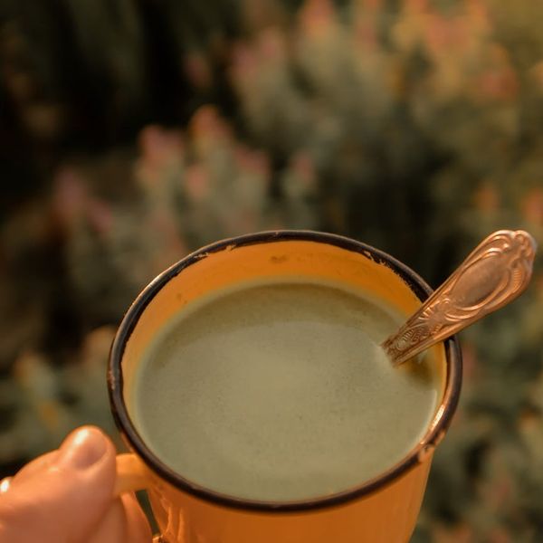 Hand holding a smooth ceramic cup of herbal tea